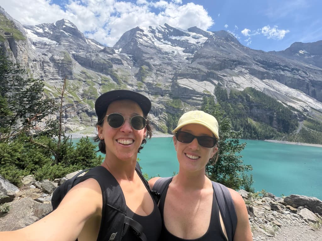Allison McCormack and Katie Gross smiling on a hike beside a turquoise mountain lake